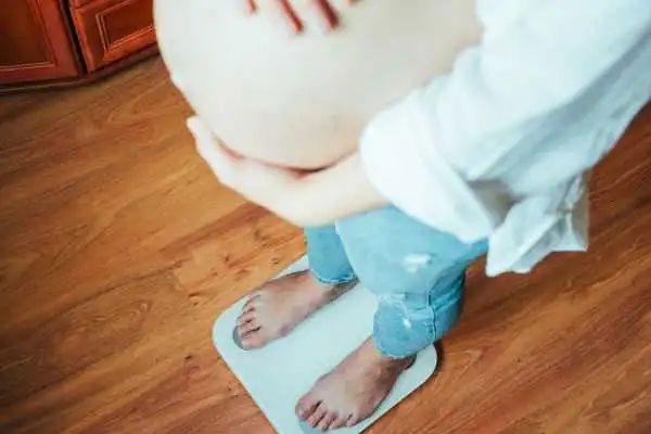 Image of woman weighing herself and experiencing weight gain through pregnancy Chester